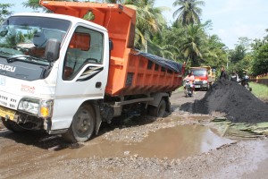 Sebuah truk pasir besi terperosok di lubang jalan yang menganga, di jalur utama Kecamatan Parigi, Senin (18/2).