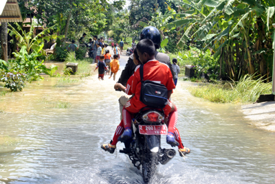 Luapan air dari saluran pembuangan tidak hanya membanjiri areal sawah di Jajawar dan Balokang, tapi juga perkampungan di sekitarnya. Tampak pengendara motor melintasi genangan air di depan kantor BPP Kec. Banjar. Foto : Eva Latifah/HR.