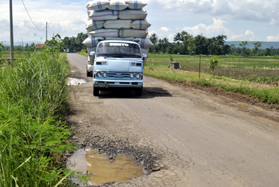 Mobil pengangkut hasil pertanian tengah melintas dibagian jalan yang berlubang. Kondisi jalan seperti itu menjadi kendala bagi aktifitas ekonomi warga sekitar. Foto : Eva Latifah/HR.