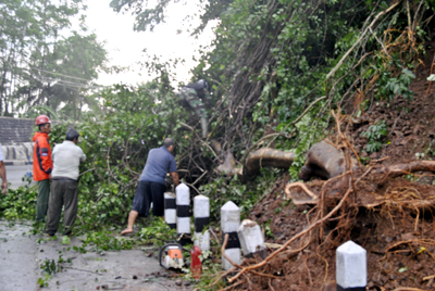 Petugas Badan Penanggulangan Bencana Daerah (BPBD) Kota Banjar, dibantu warga mengevakuasi pohon yang tumbang, serta membersihkan material tanah dari longsoran tebing. Poto diambil Senin (22/4). Foto : Pepep Riswanto Akbar/HR.