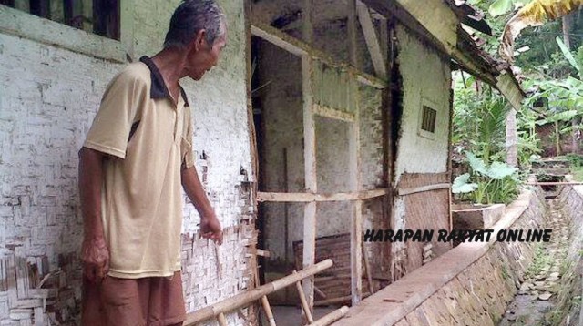 Talma (70) menunjukkan bagian dinding rumahnya yang rusak oleh rayap akibat terlalu menempel pada bangunan tembok saluran air. Foto: Eva Latifah/HR.