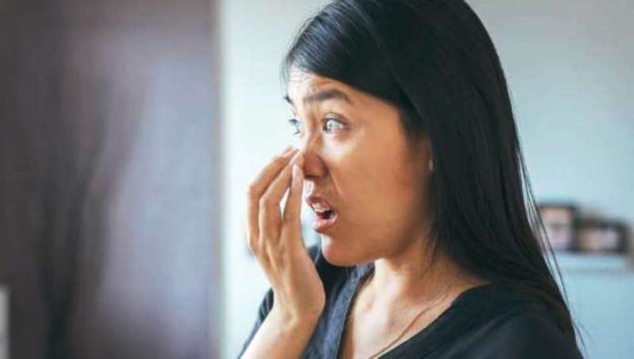 Seorang wanita sedang menghirup bau nafas akibat penyakit ketosis