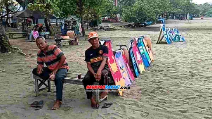 Penjual jasa sewa papan selancar di Pantai Barat Pangandaran.